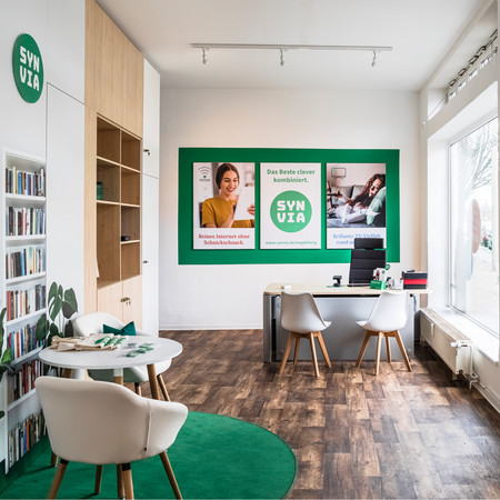 Zu sehen ist die Räumlichkeit der Firma Synvia mit Regalen, zwei Stühlen und einem Tisch. 