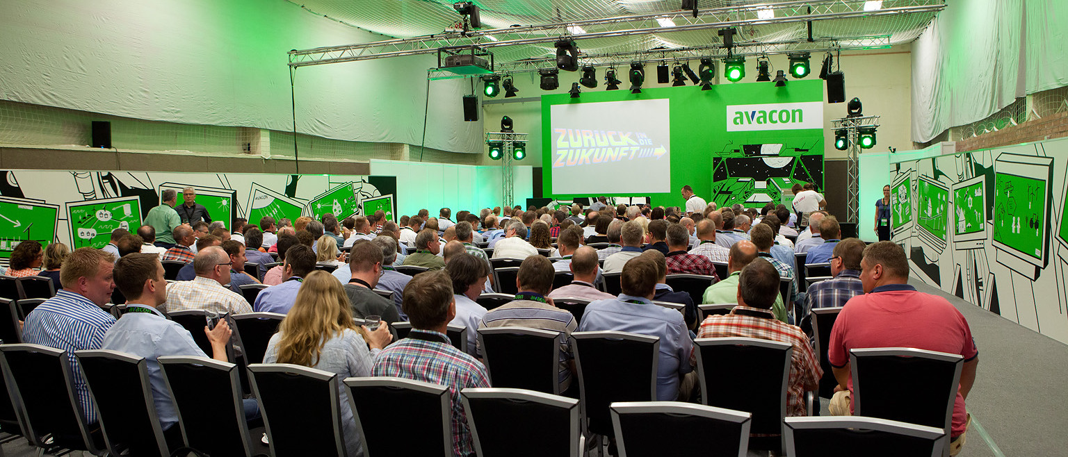 Mehrere hundert Menschen lauschen einer Präsentation der Firma Avalex auf einer Messe. 